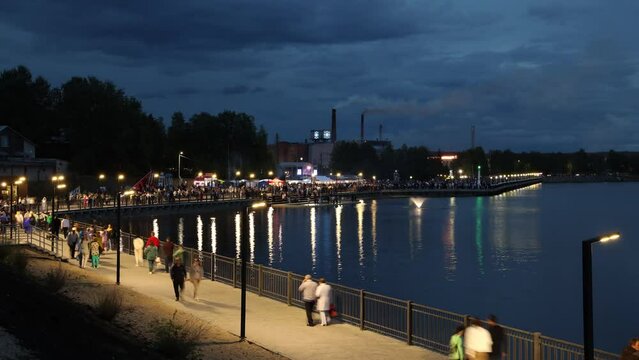 view of the embankment of the lake of the sea on a summer evening at sunset people walk timelapse