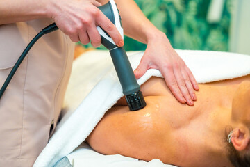 Fototapeta premium Professional masseur treating a patient with innovative shockwaves treatment