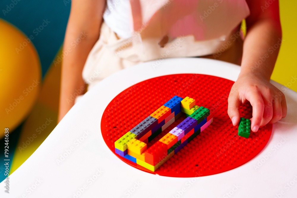 Poster child engaged in creative play with colorful building blocks on a round base