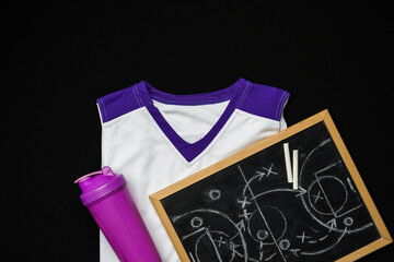 White and Purple Sports Uniform and Water Bottle Next to a Chalkboard on Black Background