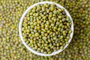 Uncooked, green mung beans in bowl. Dry mung beans grains. Top view - obrazy, fototapety, plakaty