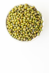 Uncooked, green mung beans in bowl on white background. Dry mung beans grains. Top view. Space for a text