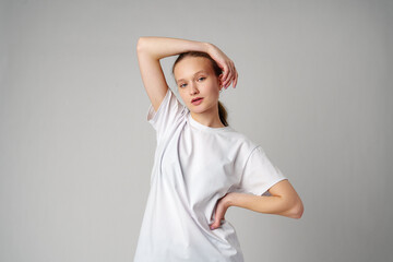 Beautiful young girl posing in white T-shirt and jeans on gray background