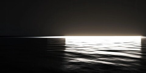 A dark ocean with a bright moon reflecting on the water