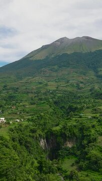 Aerial view of farmland with plantings against a background of mountains and blue sky. Kanlaon volcano. Negros, Philippines