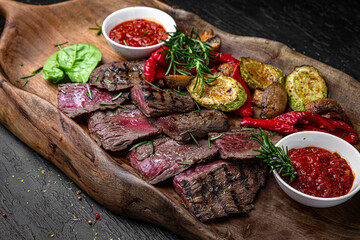  A large plateful of meaty cuts of mildly grilled steak with grilled vegetables. A set for a large...