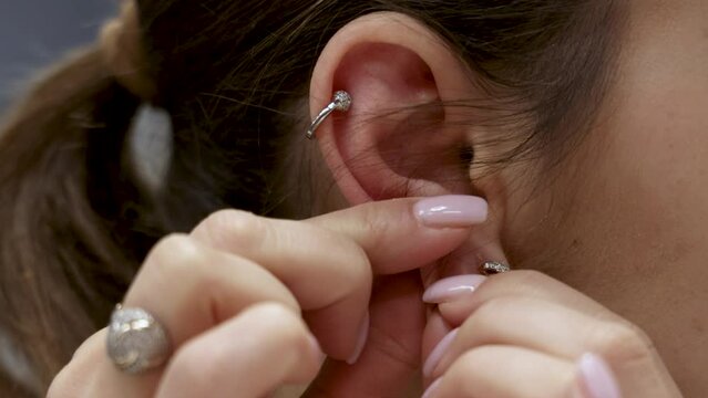 woman girl attaching upper ear piercing hoop.close up earring.4k
