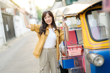 Young Asian woman backpack traveler standing a side of Tuk Tuk taxi on summer vacations at Bangkok, Thailand. Journey trip lifestyle, Asia summer tourism concept. - 792478264