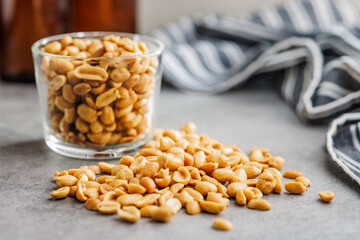 Salted roasted peanuts in glass cup on kitchen table - 792479075