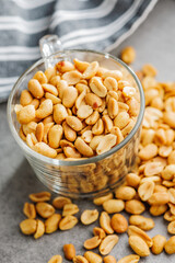 Salted roasted peanuts in glass cup on kitchen table