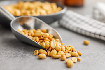 Salted roasted peanuts in scoop on kitchen table - 792480271