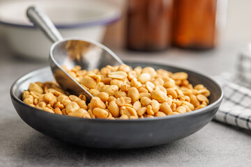 Salted roasted peanuts on plate  on kitchen table - 792480412