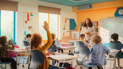 Caring Teacher Explaining a Math Lesson to a Classroom Full of Bright Diverse Children. Little Girl...