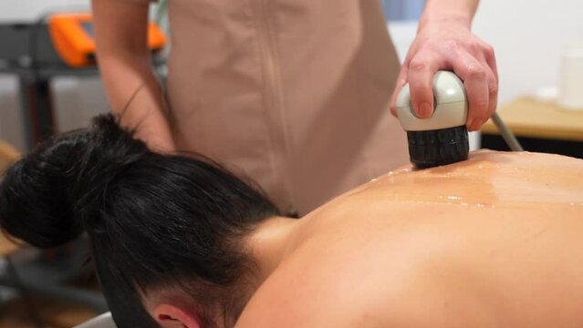 Patient lying on stretcher receiving a shockwave alternative therapy massage in a clinic