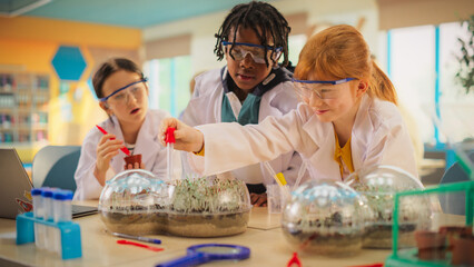 Elementary School Students Sitting Behind a Table in a Group, Conducting a Biology Experiment for a...