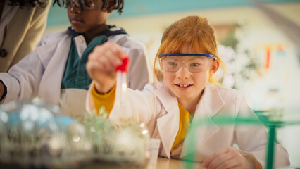 Portrait of a Cute Primary School Girl Using a Pipette to Add Nutritious Water Mix to a Set of...