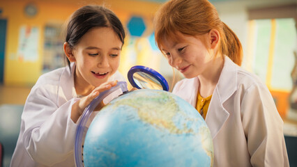 Elementary School Students Conducting Geography Class Research, Using a Globe and a Magnifying...