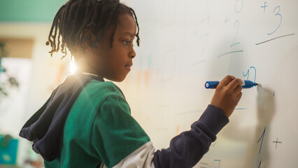 Portrait of a Handsome African Boy Finding a Solution to a Mathematical Task on a Whiteboard in...