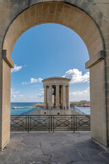 The Siege Bell War Memorial framed by an arch of the Lower Barrakka Gardens, Valletta, Malta