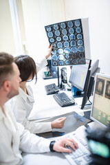 Doctors in the MRI room sit at a computer monitoring the progress of the procedure. A council of doctors examines an MRI image. Blurred image - obrazy, fototapety, plakaty