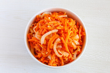 Fresh healthy vegetarian carrot salad with apple, onion and spices in the bowl. Top view, close up