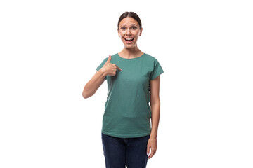 young slender european woman with ponytail hairstyle dressed in green t-shirt draws attention to advertising