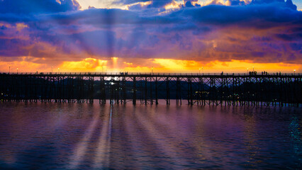 A beautiful sunset over a body of water with a pier in the foreground