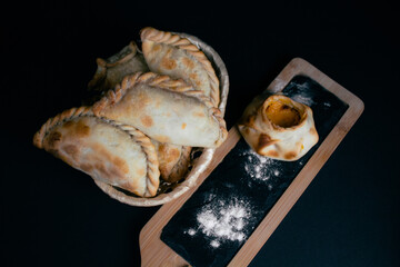 Variety of ready-to-eat empanadas, served on blackboard, flour,