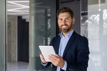 Smiling businessman with tablet in modern office setting
