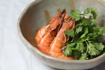 Boiled shrimp with soy sauce and coriander in a white bowl