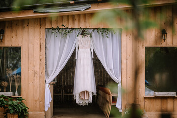 Valmiera, Latvia - August 10, 2023 - A wedding dress is displayed in an open wooden doorway draped...
