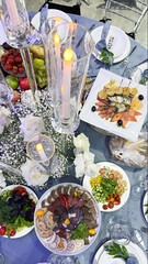 Lavishly set round table with floral centerpiece, candles, and various dishes