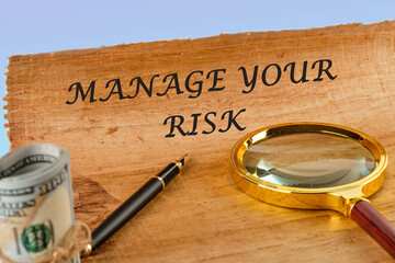 Business and manage your risk concept. Concept word Manage your risk on papyrus next to a magnifying glass and money - obrazy, fototapety, plakaty