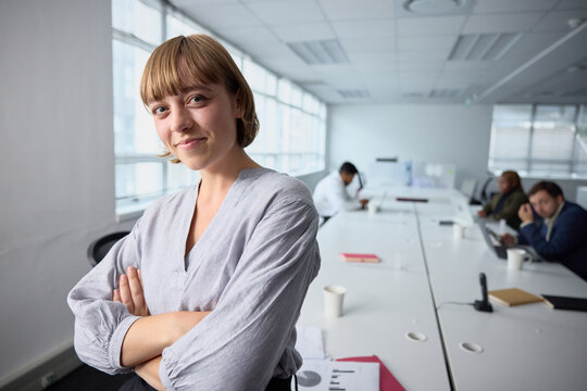 Young businesswoman in businesswear looking at camera with arms crossed in office