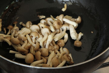 mushrooms is cooking in frying pan in restaurant kitchen