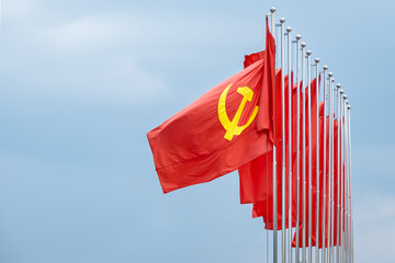 Large communist flags floating in the wind with a blue sky background