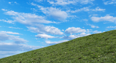 春・夏　煽りで見上げた丘・土手の野原の坂道　さわやかな晴天の青空と雲の背景　アウトドア・夏休み・祝日・行楽・観光・旅行・ウォーキング・散歩のイメージ素材