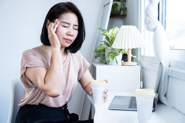 Asian woman suffering from headache after drinking coffee, caffeine effect concept