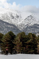 Skier glides down snowy slope with mountain backdrop under cloudy sky