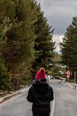 A person in a pink hat strolls on a snowy thoroughfare