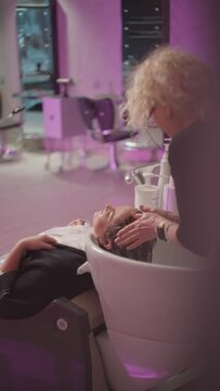 A hairdresser washes long soren women's hair in a beauty salon. Businesswoman at a barber's appointment for beauty and appearance care. High quality 4k footage