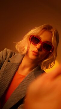 Vertical view of fashionable portrait of blonde lady in sunglasses posing. 