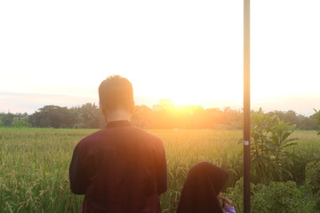 Blurry photo, a father and daughter enjoy a sunset view of the rice fields in the late afternoon