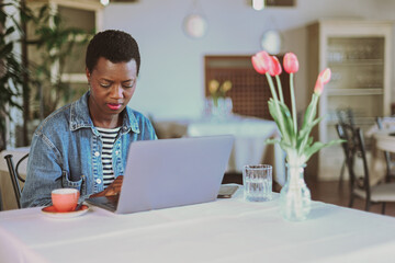 Focused young african american woman freelance use laptop at brightly lit cafe setting remote...