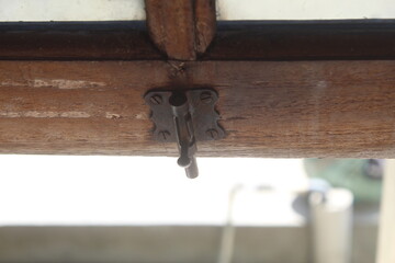 Close up of a wooden window latch against the backdrop of glittering sunlight in the morning