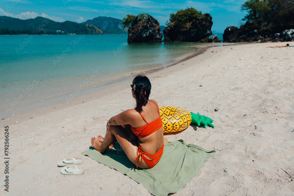 Wall mural summer vacation woman sitting and sunbathing at the beach