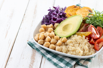 Healthy salad with avocado,lettuce,tomato and chickpeas on white wooden table. Copy space