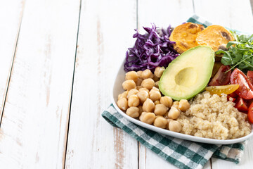 Healthy salad with avocado,lettuce,tomato and chickpeas on white wooden table. Copy space