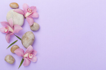 Composition with orchids and massage stones on color background, top view