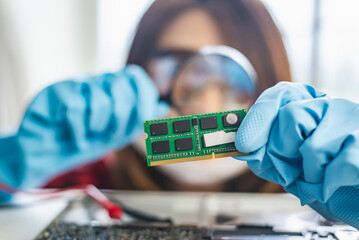 Close-up of a focused technician examining a computer RAM module with a magnifying glass in a laboratory setting. - obrazy, fototapety, plakaty